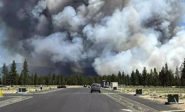 Smoke from a wildfire rises on a road near La Pine, Ore., Tuesday, June 25, 2024. The fire prompted mandatory evacuations in the small town in central Oregon and was growing rapidly in hot, dry conditions. (Jim Pharris via AP)