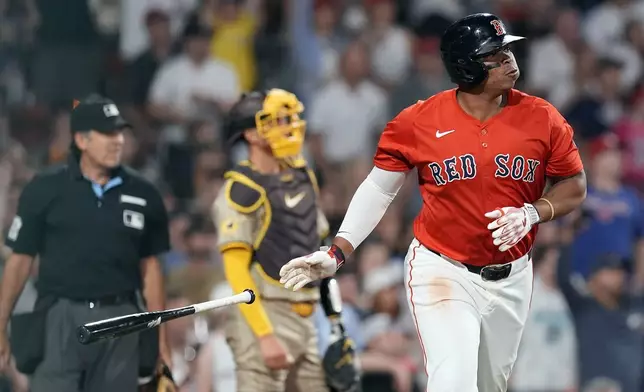 Boston Red Sox's Rafael Devers, right, watches his solo home run in front of San Diego Padres catcher Kyle Higashioka, center, during the sixth inning of a baseball game, Friday, June 28. 2024, in Boston. (AP Photo/Michael Dwyer)