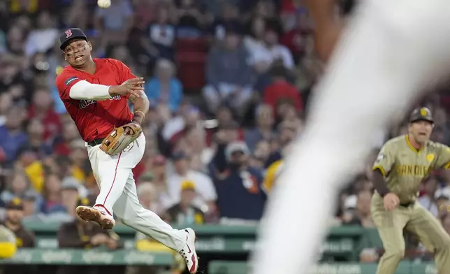 Boston Red Sox third baseman Rafael Devers, left, throws to first base on a single by Manny Machado during the fifth inning of a baseball game, Friday, June 28. 2024, in Boston. (AP Photo/Michael Dwyer)
