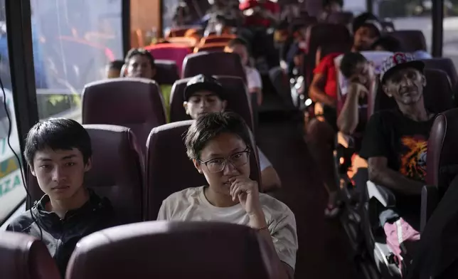 Chinese migrant Liu Tiantian, second from left, sits on a bus to Costa Rica after walking across the Darien Gap with her father and brother in Lajas Blancas, Panama, Thursday, June 27, 2024. (AP Photo/Matias Delacroix)