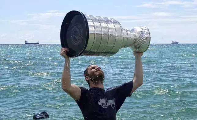 Florida Panthers NHL hockey player Matthew Tkachuk celebrates with the Stanley Cup in the Atlantic Ocean in Fort Lauderdale, Fla., Tuesday, June 25, 2024. The Panthers beat the Edmonton Oilers 2-1 on Monday night in Game 7 of the Stanley Cup Final. (Joe Cavaretta/South Florida Sun-Sentinel via AP)