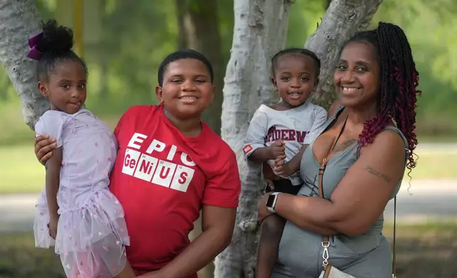 Tamika Davis, right, poses with three of her children, from left, Shanara, 3, Matthew, 11, and Lionel Jr., 2, at MLK Park in San Antonio, Thursday, May 30, 2024. Davis said friends and family watched her kids for most of her doctor visits during treatment last year for colon cancer. But she couldn't afford additional childcare, and she didn't know where to look for assistance. (AP Photo/Eric Gay)