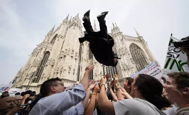 A newly ordained Catholic priest is launched in the air by friends and family outside the Duomo Cathedral after his ordination ceremony in Milan, Italy, Saturday, June 8, 2024. (AP Photo/Luca Bruno)