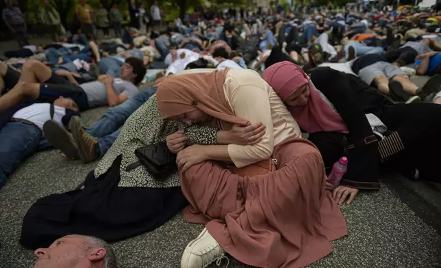 Pro-Palestinian demonstrators lie on the ground as they protest against Israeli attacks on Gaza, in Pamplona, northern Spain, on Saturday, June 8, 2024. (AP Photo/Alvaro Barrientos)