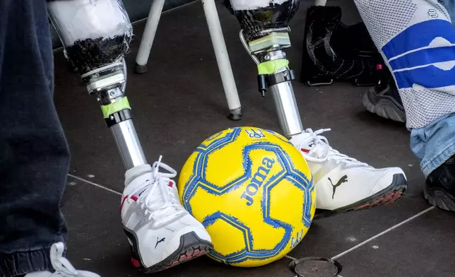 A Ukrainian war veteran with prosthetic legs watch players of Ukraine's national soccer team during a public training session in Wiesbaden, Germany, Thursday, June 13, 2024, ahead of their group E match against Romania at the Euro 2024 soccer tournament. (AP Photo/Michael Probst)