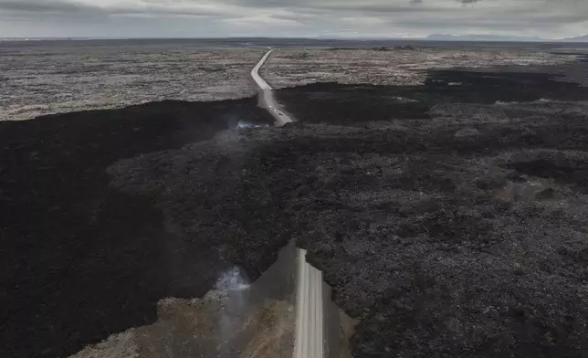 An aerial view shows lava from an active volcano engulfing the road near Grindavik, Iceland, Saturday, June 8, 2024. (AP Photo/Marco di Marco)