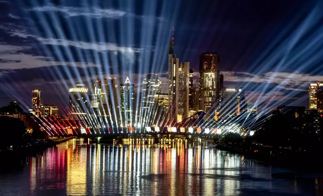 A test run of a light show illuminates the sky and the river Main in Frankfurt, Germany, late Tuesday, June 11, 2024. The show is part of the city's entertainment program on occasion of the Euro 2024 soccer tournament and will take place every evening during the tournament. (AP Photo/Michael Probst)