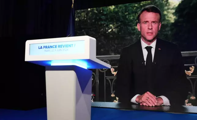 French President Emmanuel Macron appears on a television screen at the French far-right National Rally party election night headquarters, Sunday, June 9, 2024 in Paris. French President Emanuel Macron dissolved the National Assembly and called a new legislative election after defeat in the EU vote. (AP Photo/Lewis Joly)