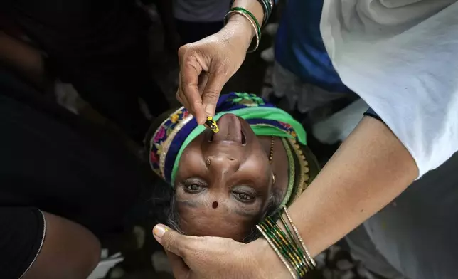 An asthma patient is administered a traditional "fish medicine" in Hyderabad, India, Saturday, June 8, 2024. Every year thousands of asthma patients arrive here to receive this fish therapy from the Bathini Goud family, which keeps a secret formula of herbs, handed down by generations only to family members. The herbs are inserted in the mouth of a live sardine, or murrel fish, and slipped into the patient's throat. (AP Photo/Mahesh Kumar A.)