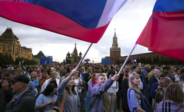 People wave Russian national flags as thousands gather on Red Square to watch a concert dedicated to the Day of Russia in Moscow, Russia, Tuesday, June 11, 2024. The Day of Russia is celebrated annually on 12 June. (AP Photo/Alexander Zemlianichenko)