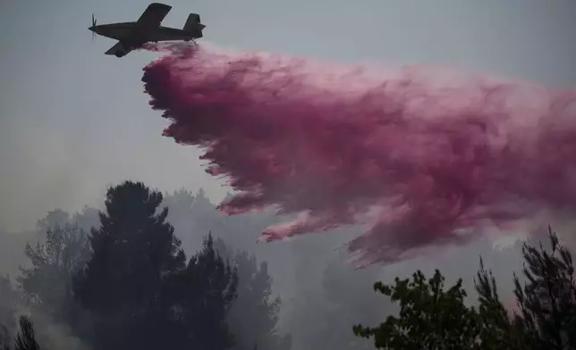 A plane uses a fire retardant to extinguish a fire burning in an area near the border with Lebanon, in Safed, northern Israel, Wednesday, June 12, 2024. Scores of rockets were fired from Lebanon toward northern Israel on Wednesday morning, hours after Israeli airstrikes killed four officials from the militant Hezbollah group including a senior military commander. (AP Photo/Leo Correa)