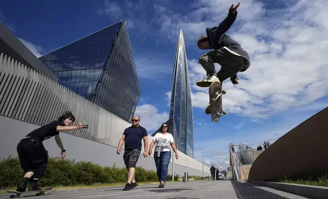 A boy jumps with a skateboard near the Lakhta Center skyscraper, the headquarters of Russian gas monopoly Gazprom in St. Petersburg, Russia, Wednesday, June 12, 2024. (AP Photo/Dmitri Lovetsky)