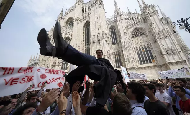 A newly ordained Catholic priest is launched in the air by friends and family outside the Duomo Cathedral after the ordination ceremony in Milan, Italy, Saturday, June 8, 2024. (AP Photo/Luca Bruno)