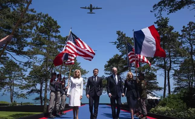 U.S. President Joe Biden, , center right, first lady Jill Biden, right, French President Emmanuel Macron, center left, and his wife Brigitte Macron walk on stage during ceremonies to mark the 80th anniversary of D-Day, Thursday, June 6, 2024, in Normandy. (AP Photo/Evan Vucci)