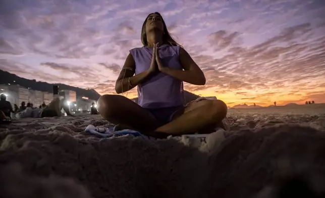 A woman sits in lotus prayer pose during the "Yoga at the Sunrise" event on Copacabana beach, in Rio de Janeiro, Saturday, June 22, 2024. The activity celebrates International Yoga Day proclaimed by the United Nations as June 21. (AP Photo/Bruna Prado)