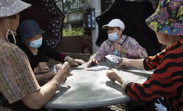 Women play cards in a public park near a remembrance ceremony for Vincent Chin in Chinatown, Sunday, June 23, 2024, in Boston. Over the weekend, vigils were held across the country to honor the memory of Chin, who was killed by two white men in 1982 in Detroit. (AP Photo/Michael Dwyer)