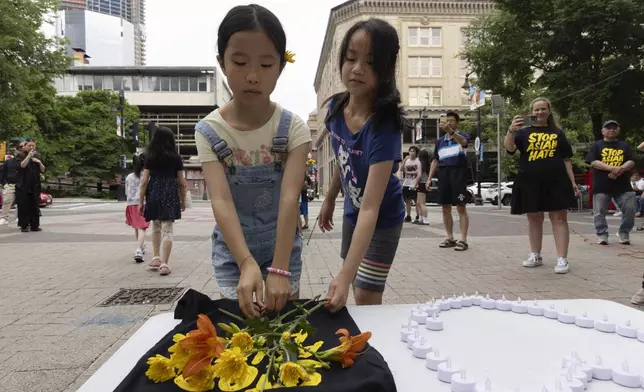 Children place flowers during a remembrance ceremony for Vincent Chin in Chinatown, Sunday, June 23, 2024, in Boston. Over the weekend, vigils were held across the country to honor the memory of Chin, who was killed by two white men in 1982 in Detroit. (AP Photo/Michael Dwyer)