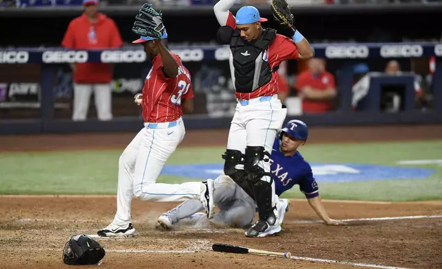 Miami Marlins pitcher Huascar Brazoban (31) steps on home plate as Marlins catcher Johnny Pereda, front right, steps aside to force out Texas Rangers' Corey Seager, bottom, during the ninth inning of a baseball game, Saturday, June 1, 2024, in Miami. (AP Photo/Michael Laughlin)