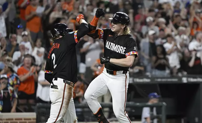 Baltimore Orioles' Heston Kjerstad, right, celebrates after his grand slam off Texas Rangers pitcher Michael Lorenzen with Gunnar Henderson (2) during the fifth inning of a baseball game, Saturday, June 29, 2024, in Baltimore. (AP Photo/Terrance Williams)