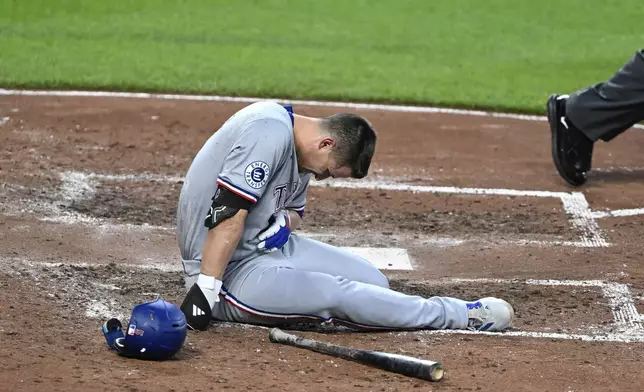 Texas Rangers' Corey Seager sits on the ground after being hit by a pitch thrown by Baltimore Orioles pitcher Cade Povich during the fifth inning of a baseball game, Saturday, June 29, 2024, in Baltimore. (AP Photo/Terrance Williams)