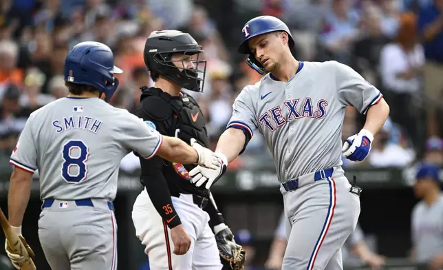 Texas Rangers' Corey Seager, right, is greeted by Josh Smith (8) after hitting a solo home run off Baltimore Orioles pitcher Cade Povich during the first inning of a baseball game, Saturday, June 29, 2024, in Baltimore. (AP Photo/Terrance Williams)