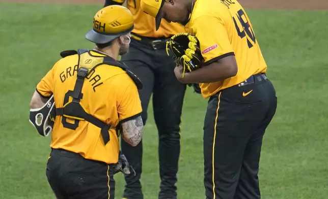 Pittsburgh Pirates relief pitcher Luis L. Ortiz, right, is joined by catcher Yasmani Grandal, left, and third baseman Ke'Bryan Hayes waiting for manager Derek Shelton to remove him from the baseball game against the Tampa Bay Rays during the sixth inning in Pittsburgh, Friday, June 21, 2024. (AP Photo/Gene J. Puskar)