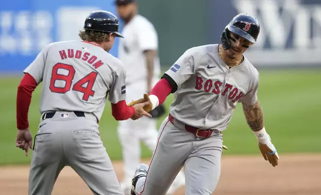 Boston Red Sox third base coach Kyle Hudson greets Jarren Duran at third after Duran's home run off Chicago White Sox starting pitcher Jake Woodford during the first inning of a baseball game Thursday, June 6, 2024, in Chicago. (AP Photo/Charles Rex Arbogast)