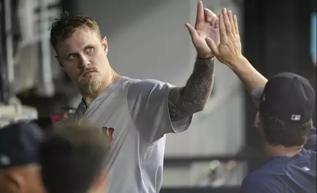 Boston Red Sox starting pitcher Tanner Houck, left, high-fives fellow pitcher Kutter Crawford in the dugout after the third inning of the team's baseball game against the Chicago White Sox on Thursday, June 6, 2024, in Chicago. (AP Photo/Charles Rex Arbogast)