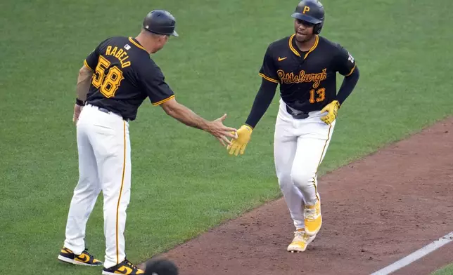 Pittsburgh Pirates' Ke'Bryan Hayes (13) rounds third base to greetings from third base coach Mike Rabelo after hitting a solo home run off Cincinnati Reds starting pitcher Nick Lodolo during the seventh inning of a baseball game in Pittsburgh, Tuesday, June 18, 2024. (AP Photo/Gene J. Puskar)
