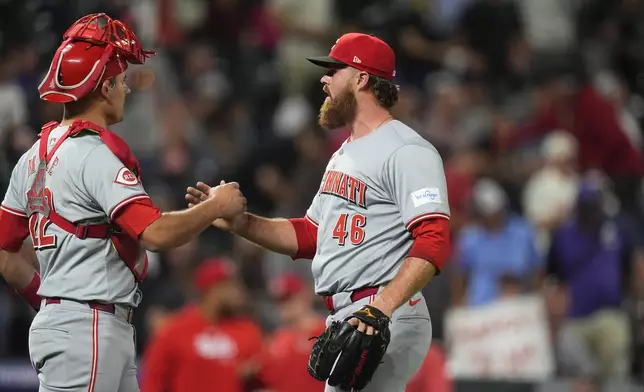 Cincinnati Reds catcher Luke Maile, left, congratulates relief pitcher Buck Farmer after the team's baseball game against the Colorado Rockies on Tuesday, June 4, 2024, in Denver. (AP Photo/David Zalubowski)