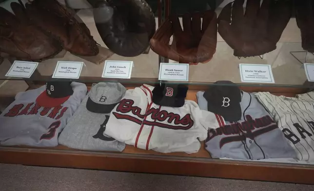 Former uniforms of the Birmingham Barons baseball team and gloves are on display in a shop near Rickwood Field, Monday, June 10, 2024, in Birmingham, Ala. Rickwood Field, known as one of the oldest professional ballpark in the United States and former home of the Birmingham Black Barons of the Negro Leagues, will be the site of a special regular season game between the St. Louis Cardinals and San Francisco Giants on June 20, 2024. (AP Photo/Brynn Anderson)