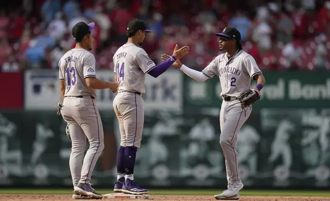 Colorado Rockies' Alan Trejo (13), Ezequiel Tovar (14) and Greg Jones (2) celebrate a 6-5 victory over the St. Louis Cardinals in a baseball game Saturday, June 8, 2024, in St. Louis. (AP Photo/Jeff Roberson)