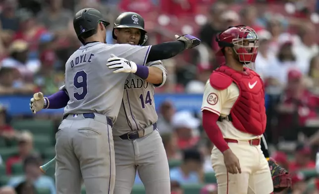 Colorado Rockies' Ezequiel Tovar (14) gets a hug from teammate Brenton Doyle (9) after hitting a two-run home run as St. Louis Cardinals catcher Ivan Herrera, right, stands by during the seventh inning of a baseball game Saturday, June 8, 2024, in St. Louis. (AP Photo/Jeff Roberson)