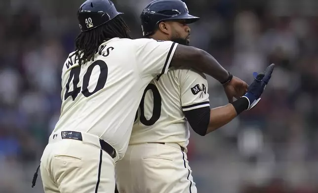 Minnesota Twins' Carlos Santana, right, celebrates with third base coach Tommy Watkins after hitting a three-run double during the first inning of a baseball game against the Colorado Rockies, Wednesday, June 12, 2024, in Minneapolis. (AP Photo/Abbie Parr)