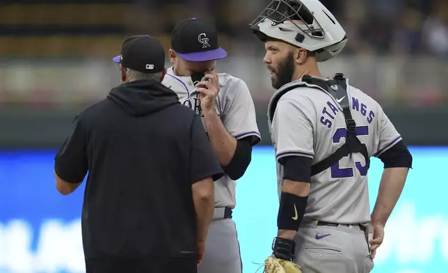 Colorado Rockies starting pitcher Austin Gomber, back, center, waits as pitching coach Darryl Scott, left, comes to the mound during the first inning of a baseball game against the Minnesota Twins, Wednesday, June 12, 2024, in Minneapolis. At right is catcher Jacob Stallings. (AP Photo/Abbie Parr)