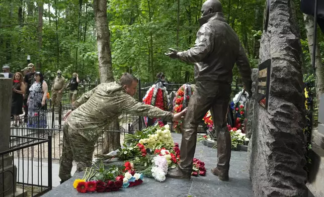 FILE - A fighter of the Wagner private military force touches a sculpture of Russian mercenary chief Yevgeny Prigozhin at his grave at the Porokhovskoye Cemetery in St. Petersburg, Russia, on Saturday, June 1, 2024. Prigozhin died in a suspicious air crash on Aug. 23, 2023, two months after launching a brief armed rebellion against the Russian military leadership. (AP Photo/Dmitri Lovetsky, File)