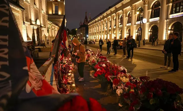 FILE - A young woman lights a candle as others stand at a makeshift memorial near the Kremlin in Moscow, Russia, on Aug. 29, 2023, for members of the Wagner Group military contractor killed in a plane crash. Among the 10 people killed in the crash was Wagner chief Yevgeny Prigozhin, who two months earlier had launched a brief rebellion against Russia’s military leadership. (AP Photo/Alexander Zemlianichenko, File)