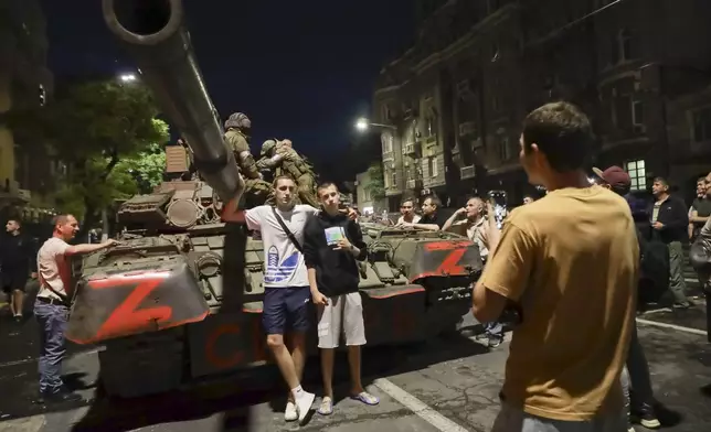 FILE – Mercenaries from the Wagner Group, a private military contractor, sit on a tank in Rostov-on-Don, Russia, on June 24, 2023, as residents pose for a photo near the headquarters of the Southern Military District. The private military company ended a brief rebellion against some officials in the Russian Defense Ministry whom Wagner chief Yevgeny Prigozhin accused of not supplying his forces in Ukraine. (AP Photo, File)