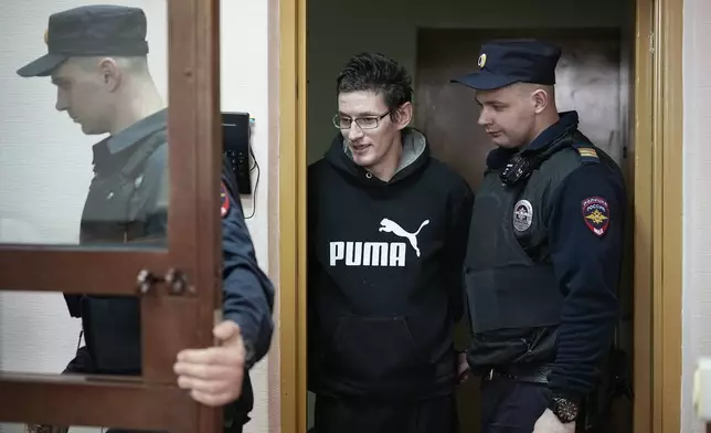 FILE - U.S. citizen Robert Woodland Romanov, center, is escorted into a defendants’ cage prior to a hearing on drug-related charges in Moscow, Russia, on April 25, 2024. Russian media reported his name matches that of a U.S. citizen interviewed by the Komsomolskaya Pravda newspaper in 2020 in which he said he was born in the Perm region in the Ural Mountains in 1991 and adopted by an American couple when he was 2. (AP Photo/Alexander Zemlianichenko, File)