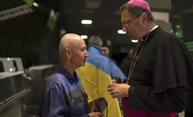 Priest Bohdan Heleta, left, who was detained inside his own church in the occupied city of Berdiansk in the Zaporizhzhia region in 2022, speaks to his friend in Kyiv airport, Ukraine, Saturday, June 29, 2024. Ten Ukrainians who had been held prisoners for years, were released from Russian captivity on Friday with a mediation of Vatican, said Ukraine's president Volodymyr Zelenskyy. (AP Photo/Alex Babenko)
