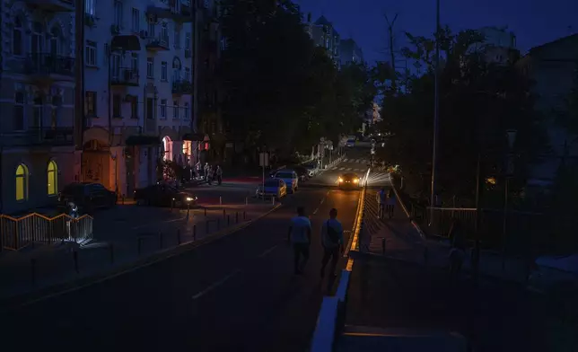 People walk along a road during a blackout in central Kyiv, Ukraine, Thursday, June 6, 2024. (AP Photo/Alex Babenko)