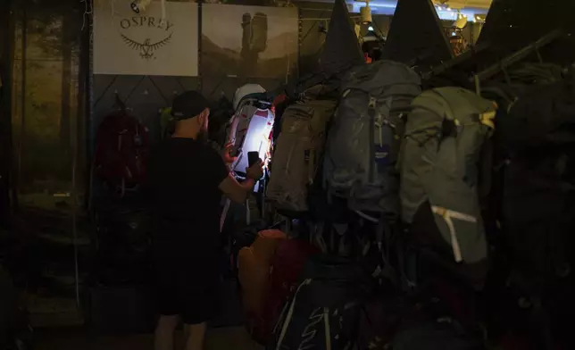 A man looks for a backpack in an outdoor equipment store during blackouts in Kyiv, Ukraine, Friday, June 7, 2024. (AP Photo/Alex Babenko)