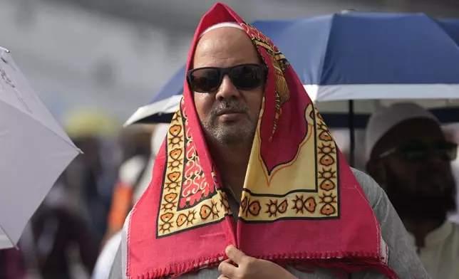 A pilgrim covers his head with a praying mat to protect himself from the sun as he leaves after offering prayers outside at the Grand Mosque during the annual Hajj pilgrimage in Mecca, Saudi Arabia, Thursday, June 13, 2024. Hajj is the annual Islamic pilgrimage to Mecca in Saudi Arabia that is required once in a lifetime of every Muslim who can afford it and is physically able to make it. Some Muslims make the journey more than once. (AP Photo/Rafiq Maqbool)