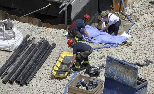 Fire personnel cover the body of a worker who fell during an accident at a building under construction in the 5600 block of South Maryland Avenue on Thursday, June 6, 2024, in Chicago. An ironworker died and another was seriously hurt Thursday after they fell off scaffolding and plunged nine stories to the ground at a University of Chicago Medicine construction site.(Antonio Perez/Chicago Tribune via AP)