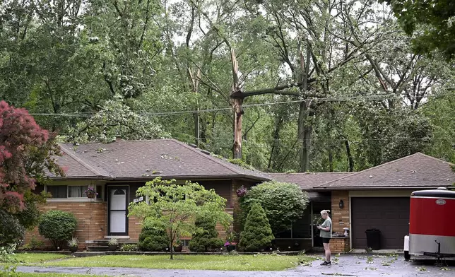 Sheri Redd stands in her driveway as fallen trees surround her home after a tornado struck the area in Livonia, Mich., Wednesday, June 5, 2024. (Robin Buckson/Detroit News via AP)