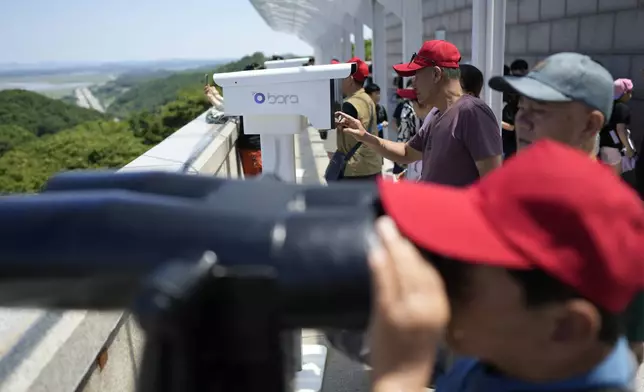 Visitors use binoculars to see the North Korean side from the unification observatory in Paju, South Korea, Tuesday, June 4, 2024. South Korea’s government has approved the suspension of a contentious military agreement with North Korea, a step that would allow it to take tougher responses to North Korean provocations. (AP Photo/Lee Jin-man)