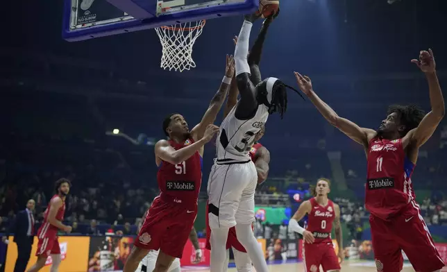 FILE - South Sudan forward Wenyen Gabriel (32) shoots from between Puerto Rico guard Tremont Waters (51) and guard Stephen Thompson Jr. (11) during a Basketball World Cup group B match at the Araneta Coliseum, Manila, Philippines, Aug. 26, 2023. It’s been only 13 years since South Sudan emerged from its second civil war to become an independent nation. (AP Photo/Aaron Favila, File)