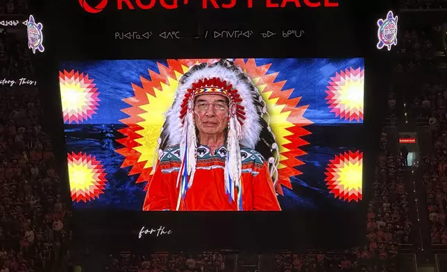 A First Nations land recognition video narrated by Chief Willie Littlechild plays on video screens prior to Game 3 of the Stanley Cup Final on Thursday, June 13, 2024, in Edmonton, Alberta. The Edmonton Oilers began airing the video prior to national athems in 2021. (AP Photo/Stephen Whyno)