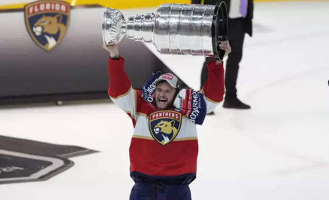 Florida Panthers center Aleksander Barkov (16) lifts the Stanley Cup trophy after Game 7 of the NHL hockey Stanley Cup Final, Monday, June 24, 2024, in Sunrise, Fla. The Panthers defeated the Oilers 2-1. (AP Photo/Rebecca Blackwell)