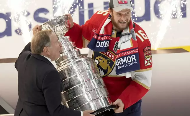 NHL Commissioner Gary Bettman, left, presents Florida Panthers forward Aleksander Barkov (16) with the NHL hockey Stanley Cup after winning the Final against the Edmonton Oilers in Sunrise, Fla., Monday, June 24, 2024. (Nathan Denette/The Canadian Press via AP)